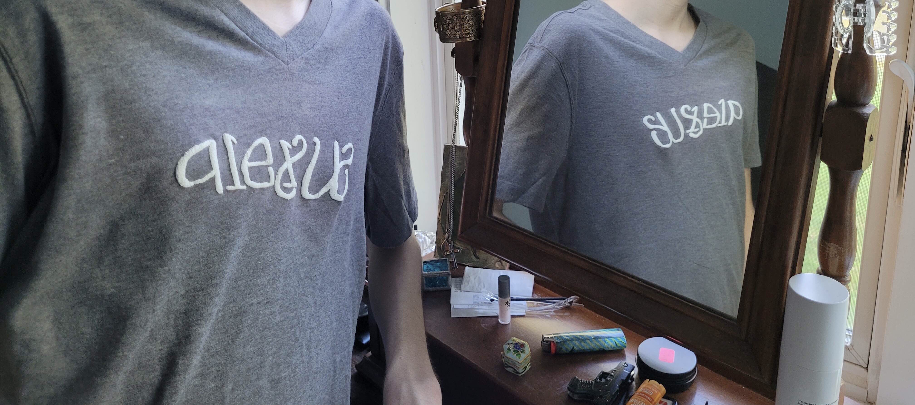 "Alex W" / "Sus1d1p" horizontal-reflection ambigram on a T-shirt and as shown in a mirror